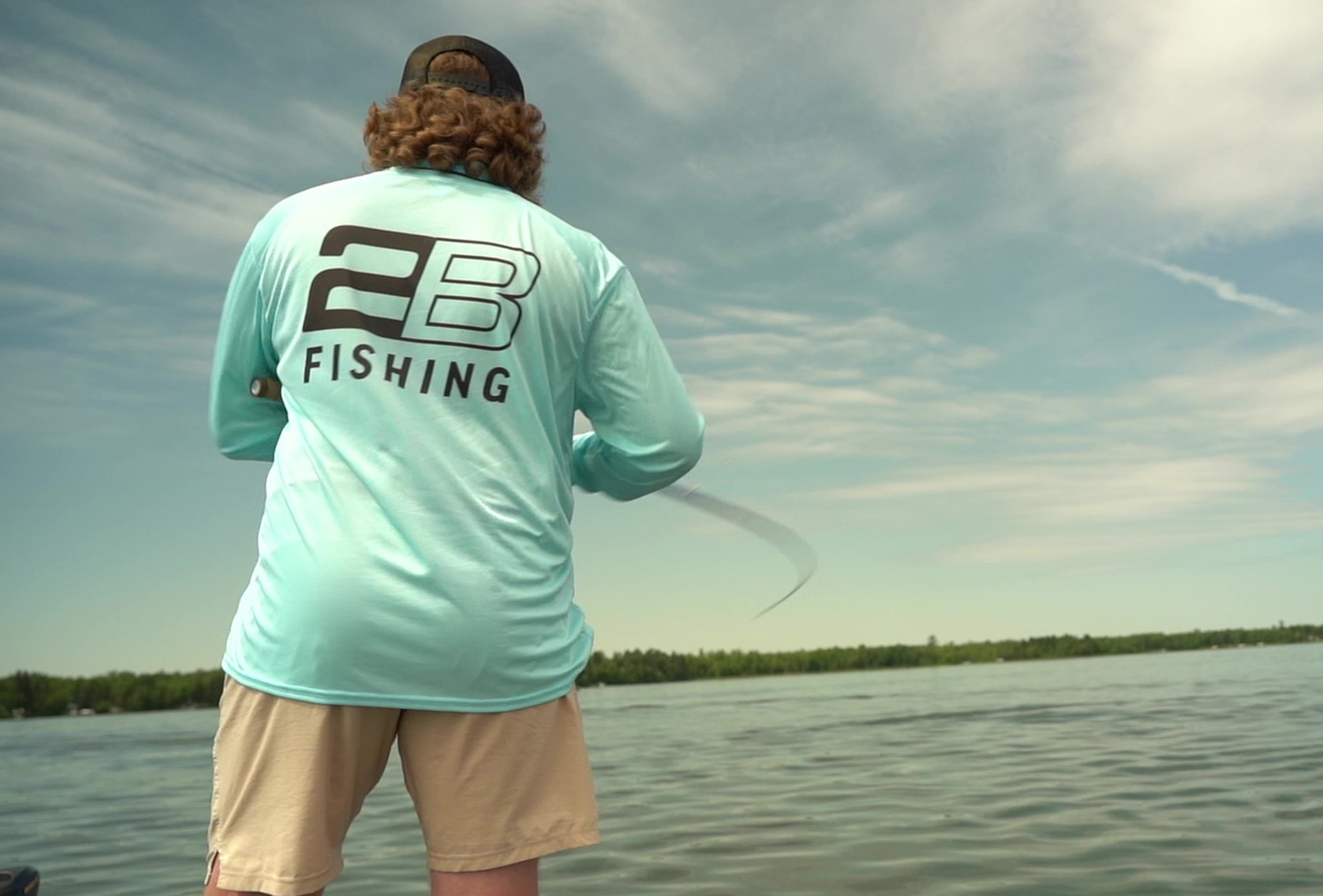 angler wearing 2B Fishing apparel reeling in a fish